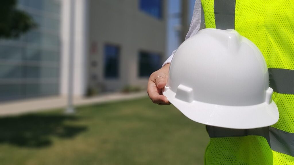 Gerencia y administración de proyectos: profesional con casco de seguridad y chaleco reflectante frente a edificio moderno