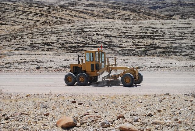 Máquina motoniveladora trabajando en una obra de movimiento de tierras en un terreno desértico