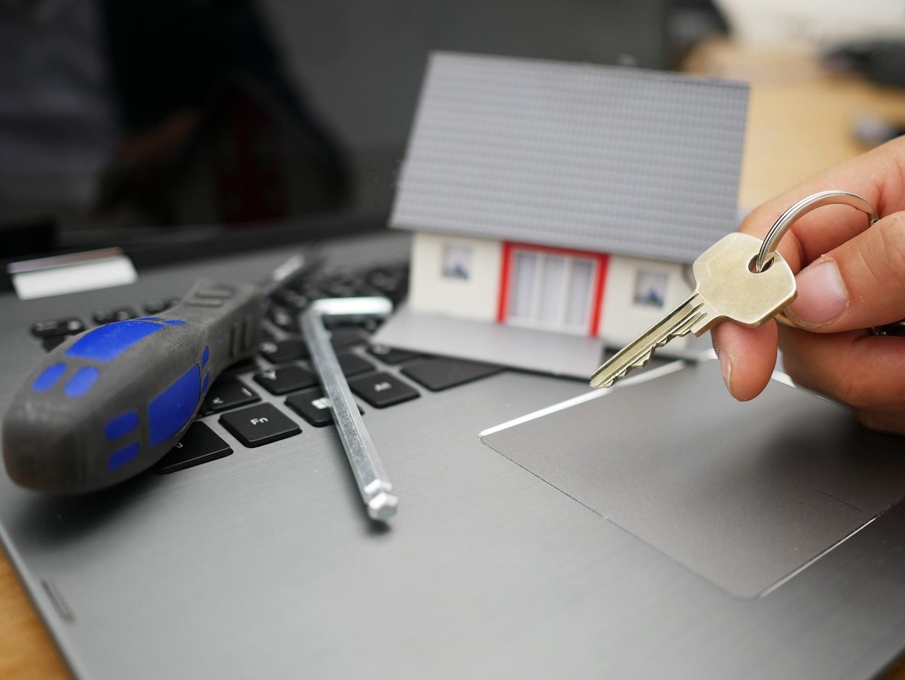 Llaves, herramientas y una maqueta de casa sobre una laptop, representando proyectos llave en mano